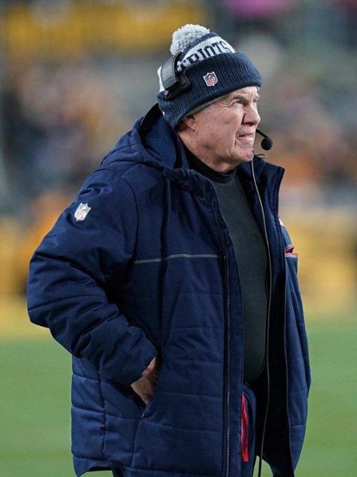 Person wearing a blue jacket and beanie with a headset on a sports field
