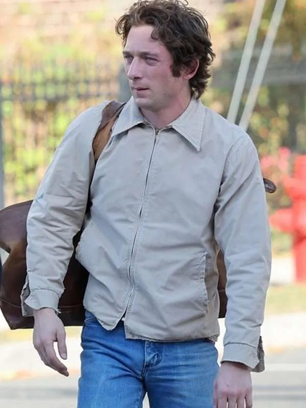 Man wearing a beige jacket and blue jeans outdoors