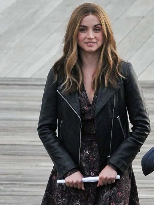 Woman wearing a black leather jacket over a floral dress, standing on a staircase.