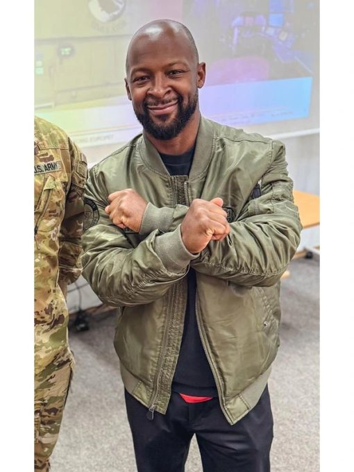 Man in a green jacket posing with clenched fists in an indoor setting