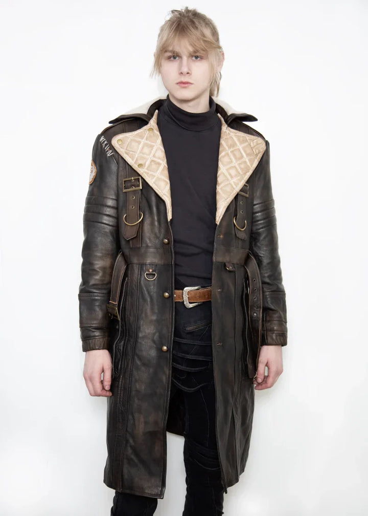 Person wearing a long leather coat with decorative elements on a white background