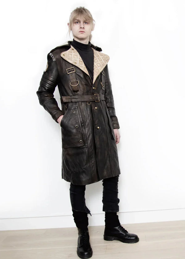 Person wearing a long black leather coat with beige lining on a white background
