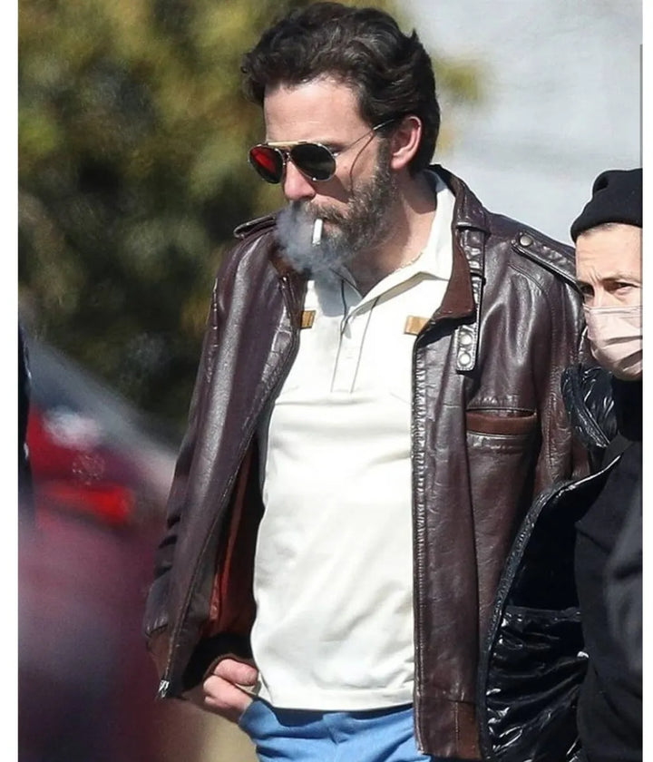 Man wearing a brown leather jacket and sunglasses outdoors