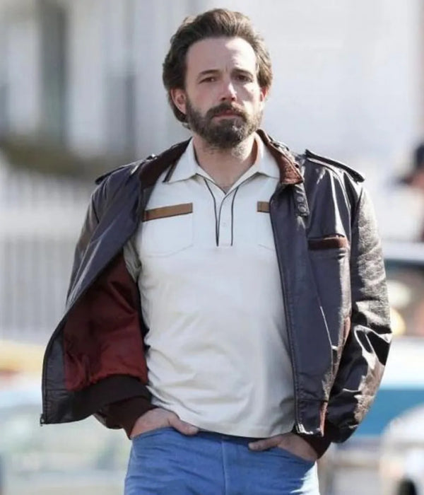 Man wearing a dark jacket over a white shirt with a blurred background